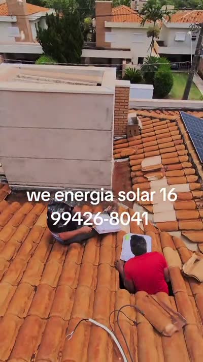 Instalador trabalhando sobre o telhado ao lado das placas solares já montadas